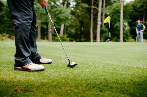 Closeup of golfer putting ball on green.