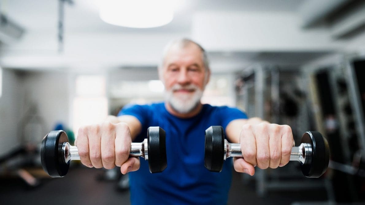 Senior man in gym working out with weights. Active Lifestyles